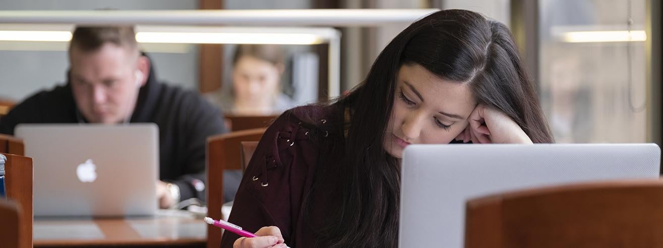 students studying in library with book and laptops