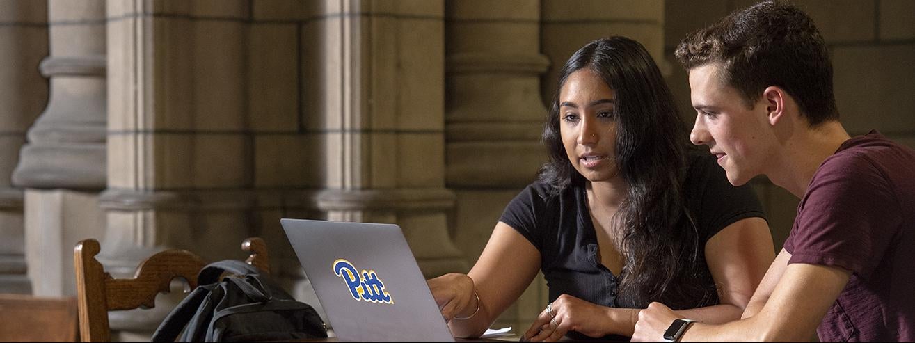 two students studying at table with laptop