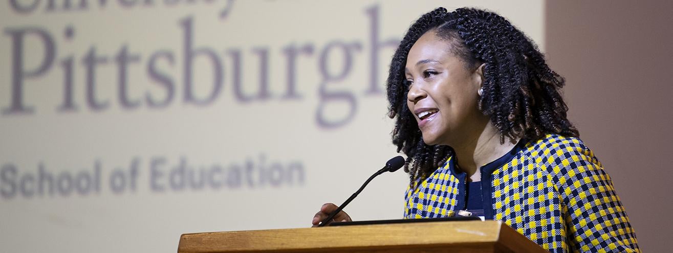 woman addressing audience from lectern on stage