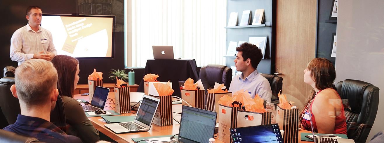 group of people around conference table looking toward presenter