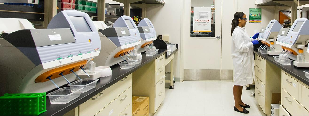 A technician works among desktop genomic sequencing machines