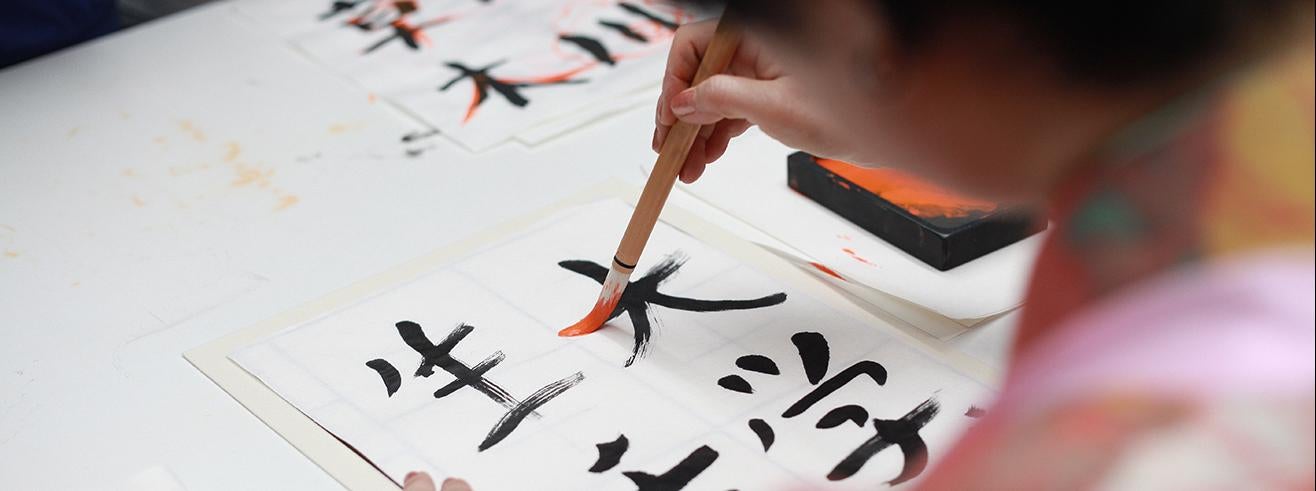 person holding brush drawing kanji script Photo by Engin Akyurt from Pexels