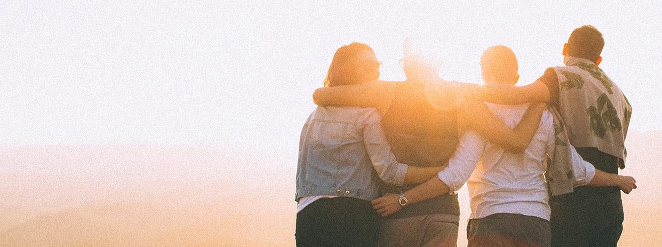 group of four linking arms in sunset