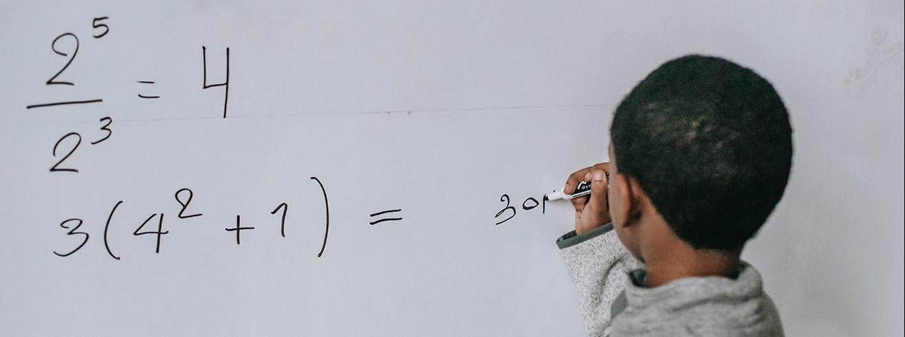 student writing math solutions on whiteboard