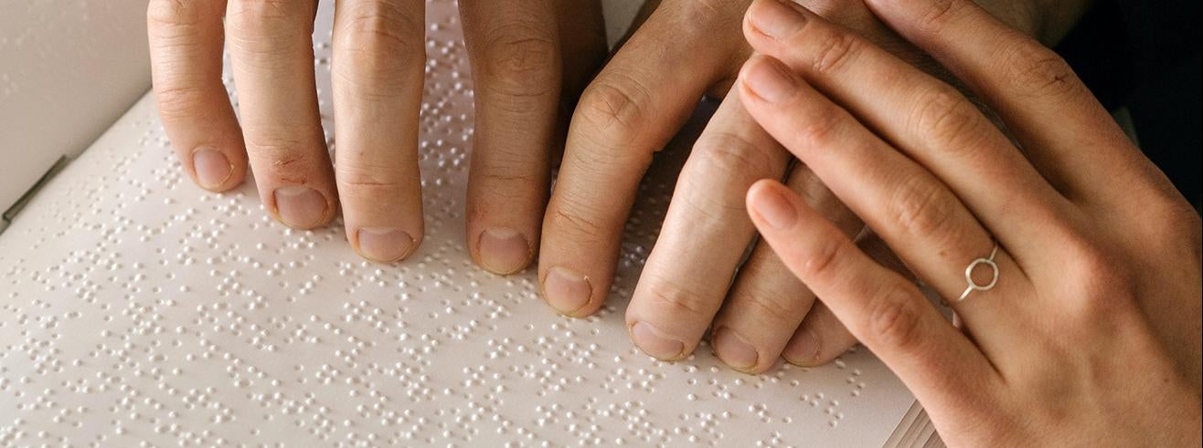 person touching and reading braille book pages