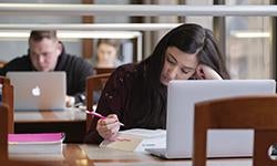 students studying in library with book and laptops