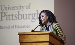 woman addressing audience from lectern on stage