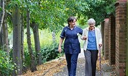 elderly woman walking with caregiver