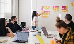 people in meeting looking at post-it notes on wall Photo by Leon on Unsplash