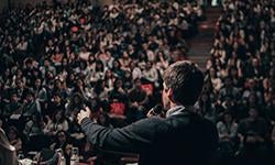 speaker presenting in front of large crowd