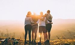 group of four linking arms in sunset