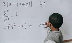 student writing math solutions on whiteboard
